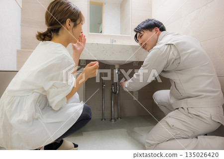 一名身穿工作服的男子和一名前來尋求維修服務的女子 一名身穿工作服的男子和一名前來尋求維修服務的女子 135026420