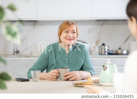 Friendly mature woman and a female guest drink tea together and talk Friendly mature woman and a female guest drink tea together and talk 135026455