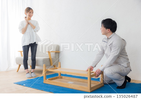 一名身穿工作服的男子和一名要求送貨的女子 一名身穿工作服的男子和一名要求送貨的女子 135026487