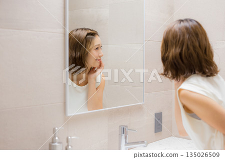 Young woman looking at a mirror 135026509