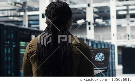 Programmer using artificial intelligence in data center to optimize network infrastructure. Server farm IT expert using AI machine learning to diagnose and resolve hardware malfunctions 135026913