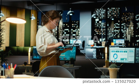 Consultant focuses on factchecking and proofreading in the strategy room standing, budgeting at night to ensure reports for business goals. Designing creative solutions for development. Camera B. 135027020