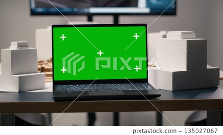 Clean workspace designed for property development with green screen laptop, showcasing empty meeting area with blueprints, 3D models and digital planning tools used for smart city projects. 135027067