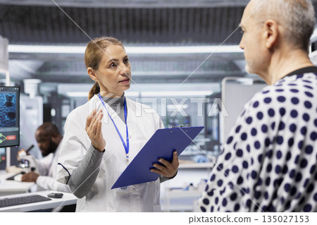 Female medic evaluates patient vitals for side effects during laboratory trial, recording dosage reactions and safety risks while supporting healthcare progress and biomedicine development. 135027153