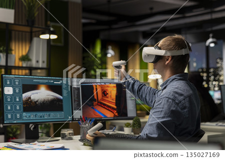 Professional male developer operating VR glasses to create spaceship station as game lobby, gaming development for the industry. AI generating modern spatial project on dual monitors. 135027169