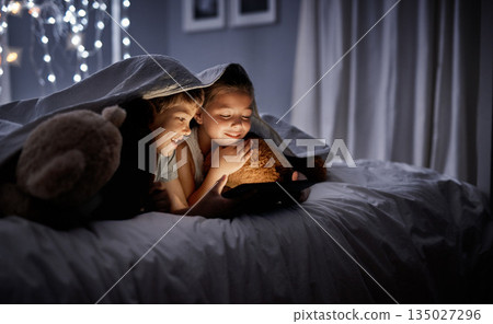 Night, tablet and siblings in bed, home or watching a movie, film or cartoon with happiness. Children, kids or brother with sister, technology or online games with a smile, dark or relax in a bedroom 135027296