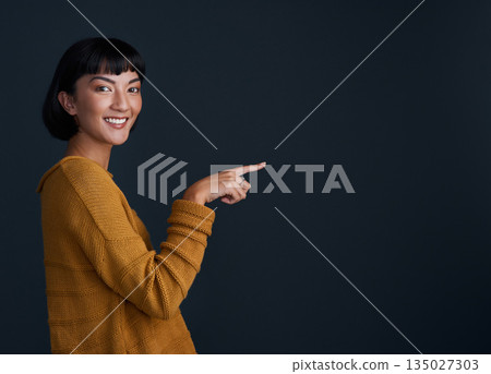 Woman is pointing, advertising and mockup space with portrait, smile and promo isolated on dark background. Happy female person, ambassador and branding with marketing and presentation in studio Woman is pointing, advertising and mockup space with portrait, smile and promo isolated on dark background. Happy female person, ambassador and branding with marketing and presentation in studio 135027303