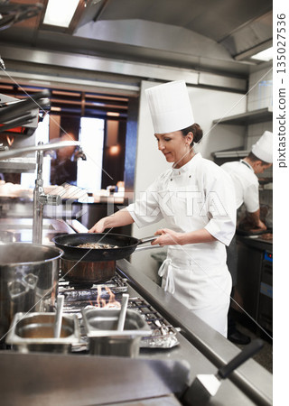 Chef, woman and frying pan in restaurant kitchen, catering service and prepare food for fine dining. Professional, cooking and female person saute meat for meal, diet and nutrition for hospitality. Chef, woman and frying pan in restaurant kitchen, catering service and prepare food for fine dining. Professional, cooking and female person saute meat for meal, diet and nutrition for hospitality. 135027536
