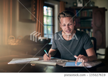 College homework, studying and a man with a tablet for research, education and elearning. Smile, working and a male student with technology for information and planning for an exam in a house College homework, studying and a man with a tablet for research, education and elearning. Smile, working and a male student with technology for information and planning for an exam in a house 135027619