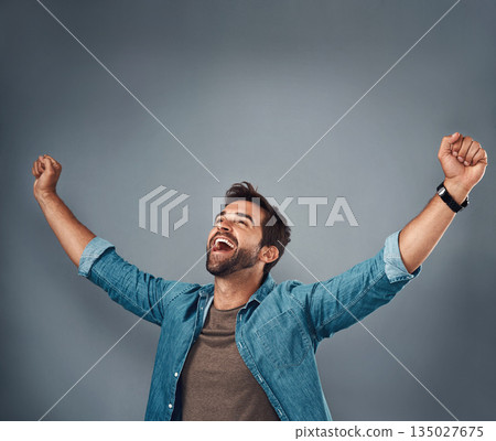 Happy man, fist and celebration for winning, success or achievement against a grey studio background. Male person screaming in victory, win or accomplishment in motivation for goals on mockup space 135027675