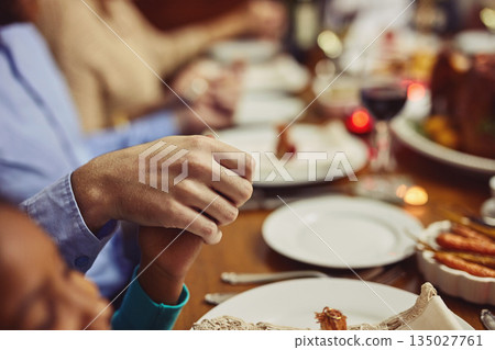 Prayer, Christmas and hand holding with family at table in dining room for holiday, food or worship. Celebration, support and gratitude with closeup of people at home for kindness, dinner and love 135027761
