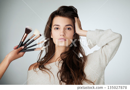 Makeup brush, face and beauty of a woman in studio with a natural glow. Portrait of a female model person on a grey background and hands for cosmetology transformation, powder cosmetics and skin care Makeup brush, face and beauty of a woman in studio with a natural glow. Portrait of a female model person on a grey background and hands for cosmetology transformation, powder cosmetics and skin care 135027878
