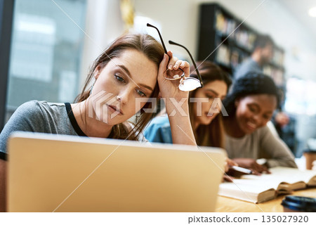 Woman, stress and laptop for studying at library, college or campus with tired face, anxiety or burnout. University student, girl and computer for education, study and fatigue at school with reading 135027920