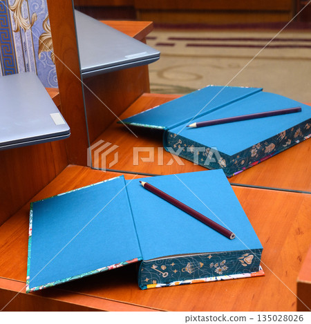 blue notebook with a pencil on a table next to a laptop blue notebook with a pencil on a table next to a laptop 135028026