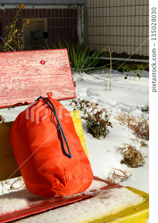 orange bag on a bright bench against a winter courtyard orange bag on a bright bench against a winter courtyard 135028030