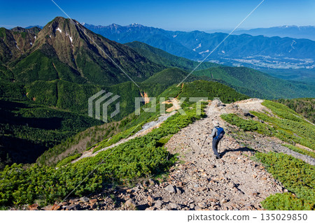 Climbers walking along the ridge of Mt. Iodake in the Yatsugatake Mountain Range and a view of Mt. Amida and the Southern Alps 135029850