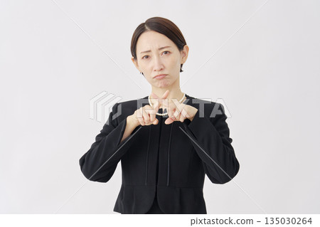 Woman in mourning clothes making a cross gesture on a white background 135030264