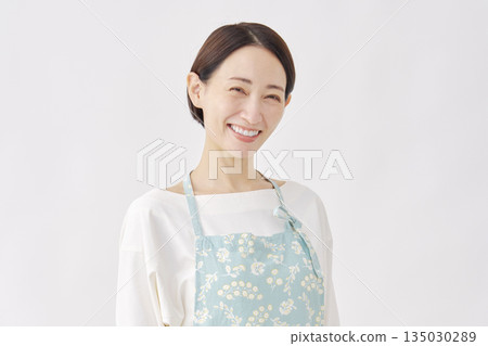 一位穿著圍裙的女子，白色背景，肖像照，看向鏡頭 135030289