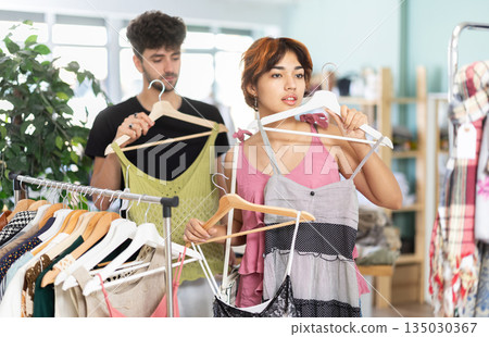 Guy helping girlfriend choose summer summer at store Guy helping girlfriend choose summer summer at store 135030367