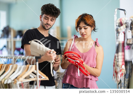 Young man advising girlfriend on choosing handbag in boutique 135030554