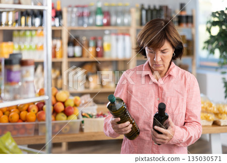 Woman chooses olive oil while shopping in grocery supermarket 135030571