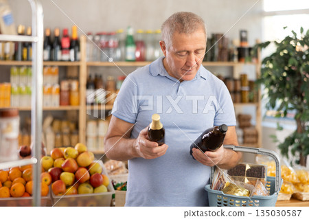 Mature man is choosing beer in grocery store Mature man is choosing beer in grocery store 135030587
