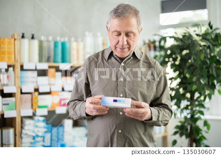 elderly man chooses an ointment at the pharmacy elderly man chooses an ointment at the pharmacy 135030607