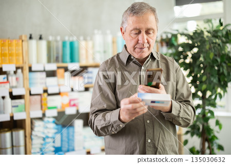 Elderly man scans ointment package 135030632