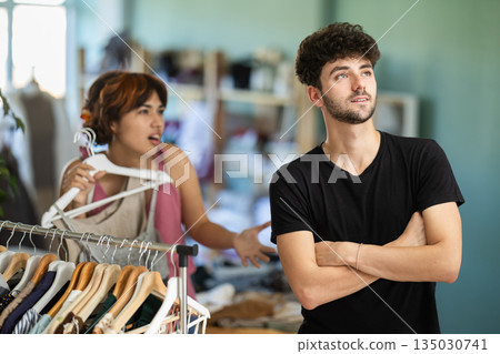Young man showing frustration during shopping with girlfriend Young man showing frustration during shopping with girlfriend 135030741