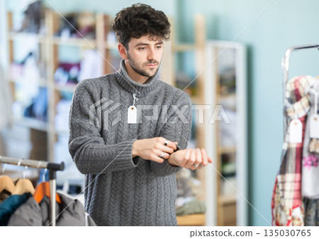 Young man trying on sweater in clothing store Young man trying on sweater in clothing store 135030765