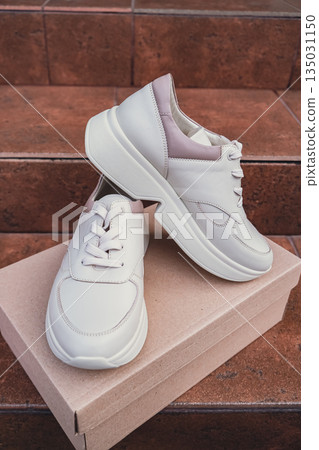 Minimalist eco-friendly white sneakers placed on recycled cardboard box, clean design for sustainable fashion concepts. New unbranded beige sneakers footwear mockups and modern product displays. For Minimalist eco-friendly white sneakers placed on recycled cardboard box, clean design for sustainable fashion concepts. New unbranded beige sneakers footwear mockups and modern product displays. For 135031150