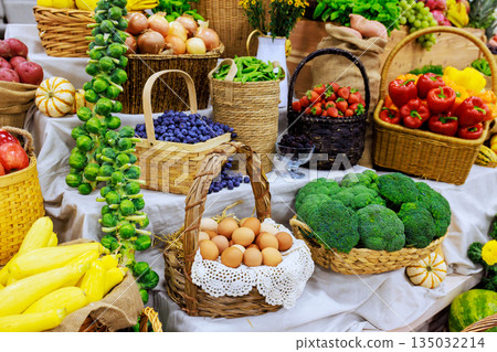 Vibrant summer fruits vegetables are beautifully arranged in baskets at marketplace. Vibrant summer fruits vegetables are beautifully arranged in baskets at marketplace. 135032214