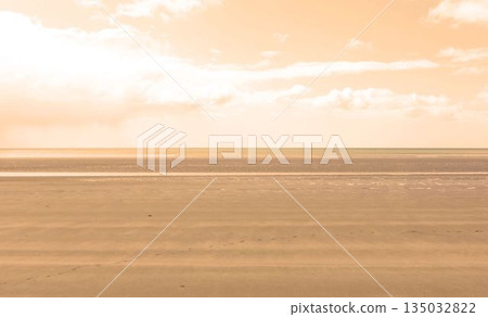 Flat design is showing vast wet sand ripples, water pools with sea horizon beneath scattered clouds Flat design is showing vast wet sand ripples, water pools with sea horizon beneath scattered clouds 135032822