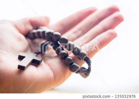 Hand holding rosary beads 135032976