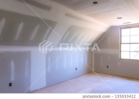Freshly constructed room with drywall installation natural light pouring in from window Freshly constructed room with drywall installation natural light pouring in from window 135033412