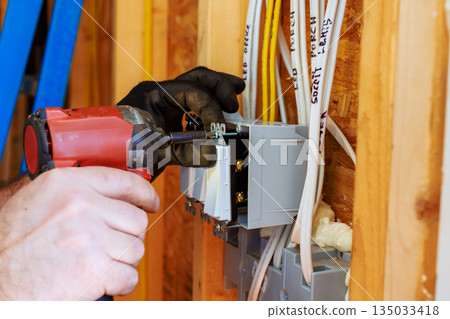 Electrician installs circuit breaker in new construction home Electrician installs circuit breaker in new construction home 135033418