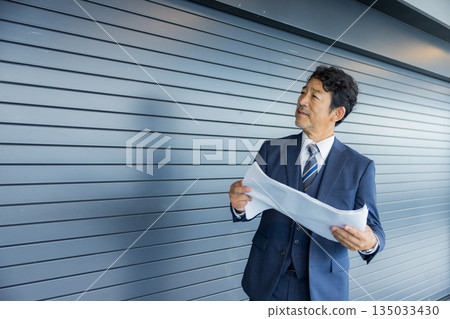 A businessman thinking in front of a store property 135033430