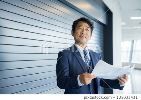 一位商人站在店鋪前沉思。 135033431