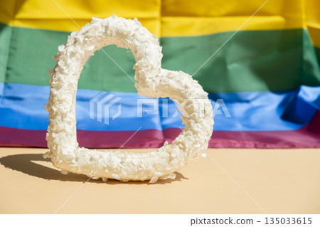 Heart made of white lilac flowers on LGBTQ flag background. Still life romantic composition of Valentines day holiday copy space for your text invitation greeting card Heart made of white lilac flowers on LGBTQ flag background. Still life romantic composition of Valentines day holiday copy space for your text invitation greeting card 135033615