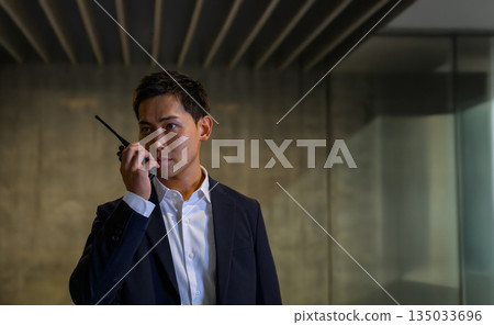 A security guard in a suit giving instructions over the radio 135033696