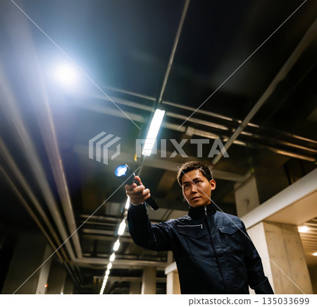 Man holding a flashlight in an underground parking lot Man holding a flashlight in an underground parking lot 135033699