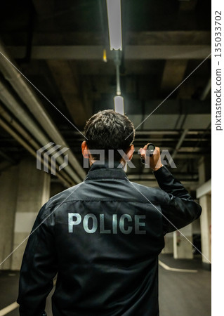 黑暗中,警察拿著手電筒。 黑暗中,警察拿著手電筒。 135033702