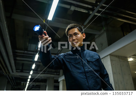 Security guard shines flashlight in the dark Security guard shines flashlight in the dark 135033717