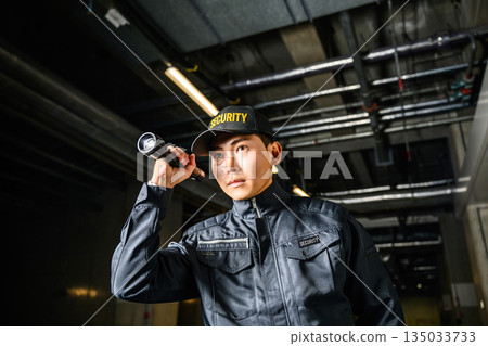 A security guard patrolling the facility at night with a flashlight A security guard patrolling the facility at night with a flashlight 135033733