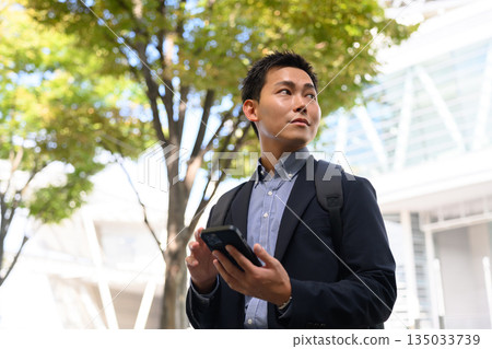 一位男性商務人士帶著智慧型手機通勤上班。 135033739