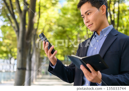 Businessman checking his schedule outdoors Businessman checking his schedule outdoors 135033744