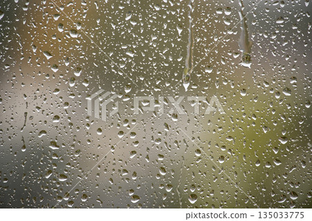 Close-Up Of Raindrops On Glass Window With Blurred Outdoor Scene Close-Up Of Raindrops On Glass Window With Blurred Outdoor Scene 135033775