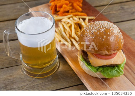 Beer mug, burger and fries on wooden table Beer mug, burger and fries on wooden table 135034330