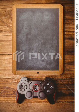 Flat vector showing blank wooden framed chalkboard on tabletop with black red game controller Flat vector showing blank wooden framed chalkboard on tabletop with black red game controller 135034394