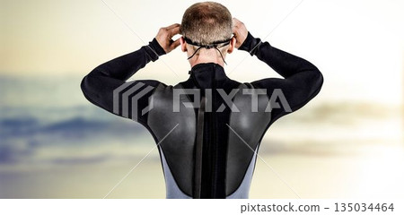 Rear view of male swimmer wearing swimming goggles at beach Rear view of male swimmer wearing swimming goggles at beach 135034464